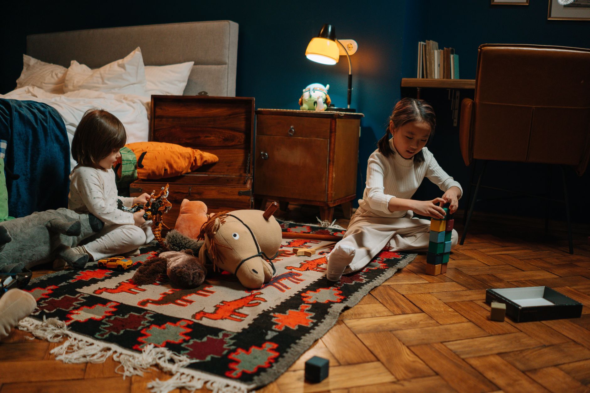 Two children in pajamas playing in a warmly lit bedroom