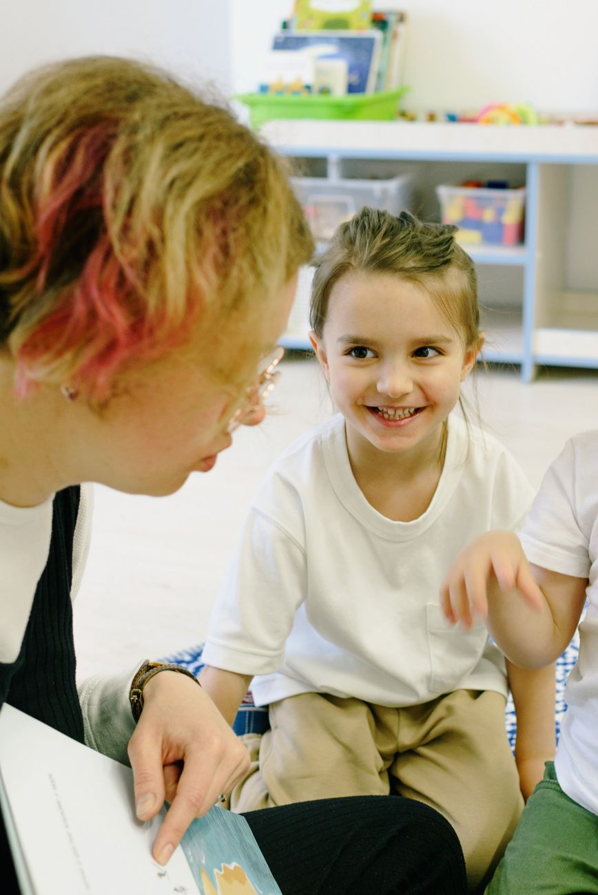 A teacher reading a picture book with young children in a kindergarten classroom